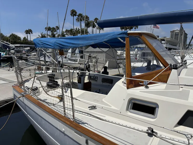 Sailboat docked at marina, Norseman 447, 1982 model, with blue canopy and wooden accents.