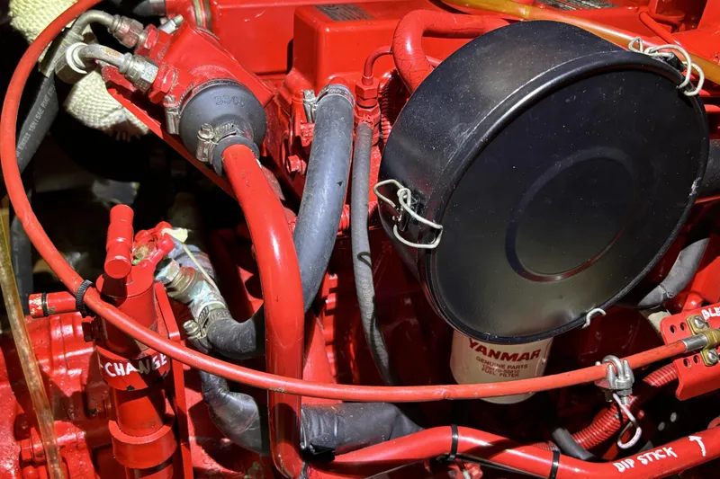 Red engine components of a 1982 Norseman 447, featuring hoses and a Yanmar fuel filter.
