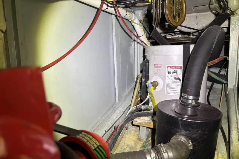 Engine compartment of a 1982 Norseman 447 with hoses and warning labels.