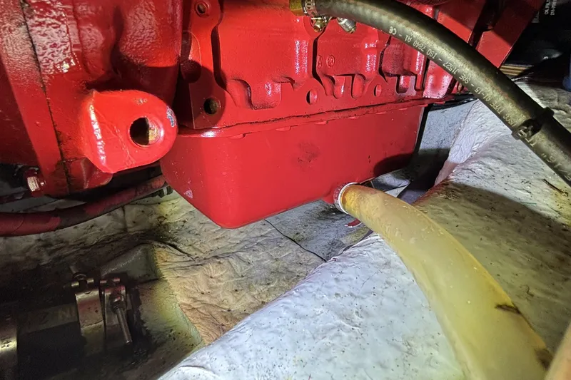 Red engine component of 1982 Norseman 447 with attached hoses in a mechanical setting.