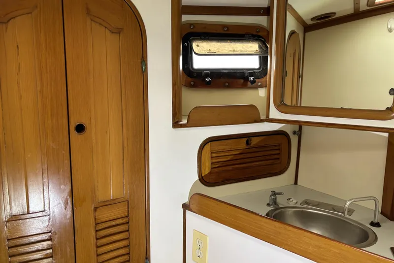 1982 Norseman 447 yacht interior with wooden cabinets, sink, and porthole window.