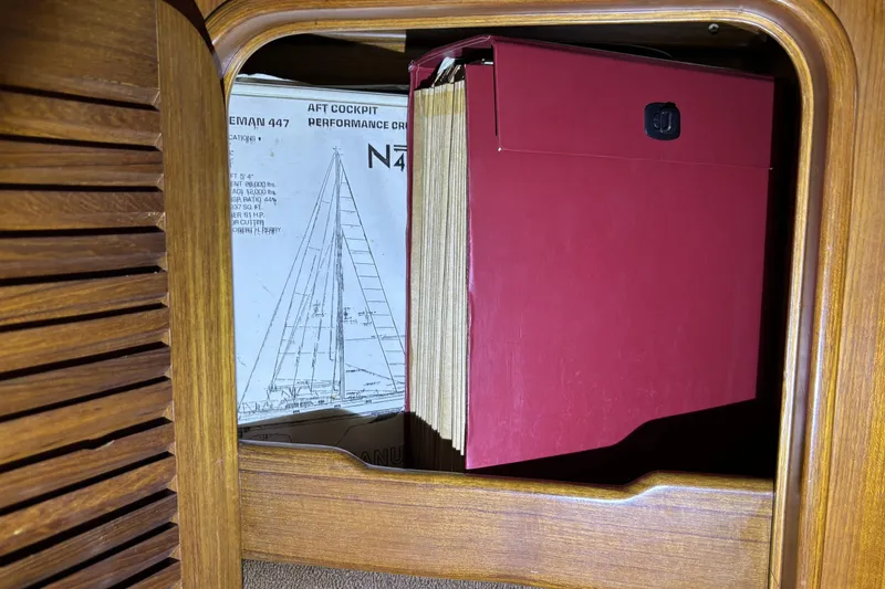 Red folder and Norseman 447 sailboat plans inside wooden cabinet.