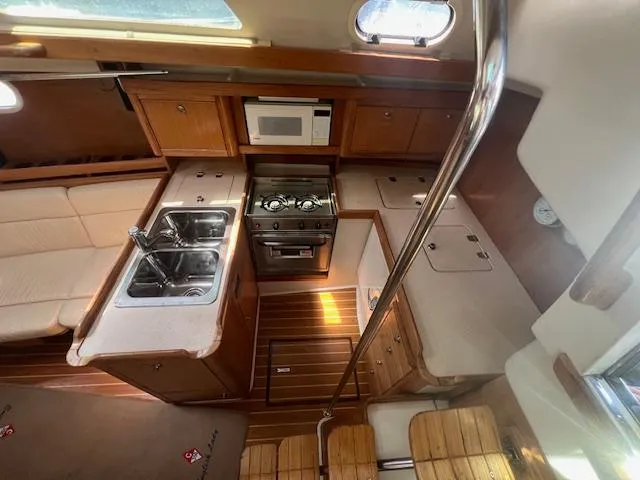 Interior of 2002 Catalina 350 yacht featuring kitchen with stove, sink, and microwave.