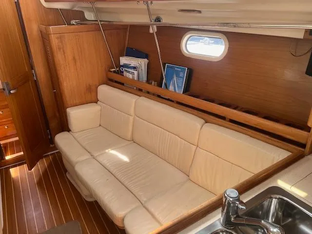 Interior of 2002 Catalina 350 yacht with beige sofa and wooden accents.