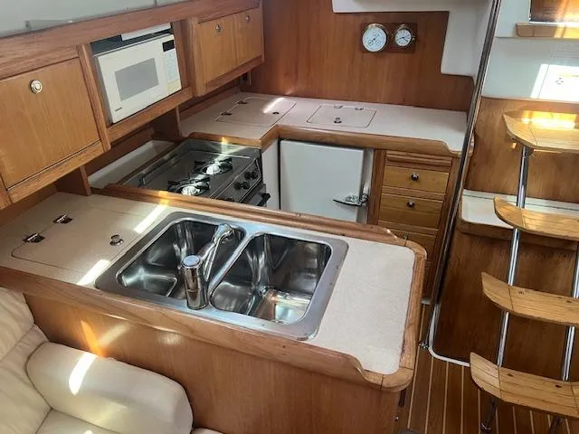 Modern kitchen in 2002 Catalina 350 yacht with wood cabinetry and stainless steel sink.