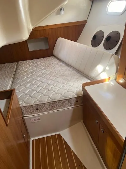 Interior cabin of a 2002 Catalina 350 sailboat with a cozy bed and wooden accents.