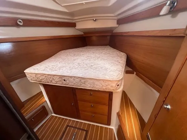 Cozy cabin interior of 2002 Catalina 350 sailboat with wooden finish and mattress.
