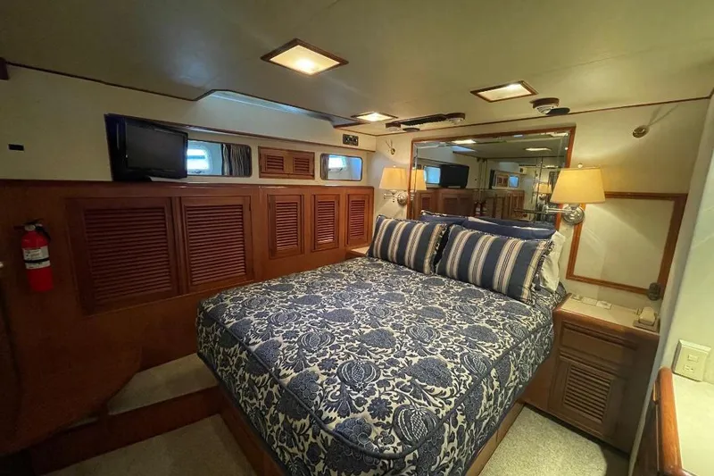 Luxurious bedroom in 1990 Offshore Yachts 55 Pilothouse with elegant bedding and wood accents.