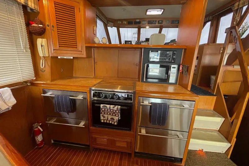 1990 Offshore Yachts 55 Pilothouse kitchen with wood cabinetry and modern appliances.