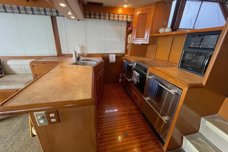 Luxurious 1990 Offshore Yachts 55 Pilothouse kitchen with modern appliances and wood finishes.