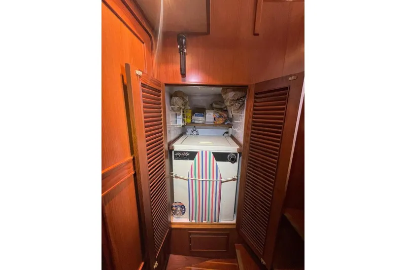 Laundry area in 1990 Offshore Yachts 55 Pilothouse with wooden cabinetry and storage shelves.