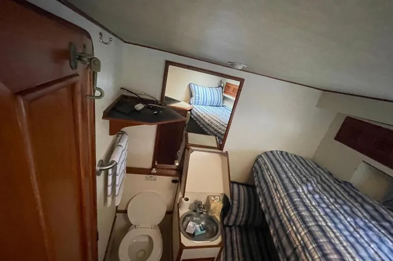 1990 Offshore Yachts 55 Pilothouse interior with bathroom and striped bedding.