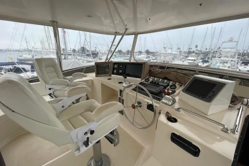Pilothouse interior of 1990 Offshore Yachts 55, featuring dual captain chairs and navigation equipment.