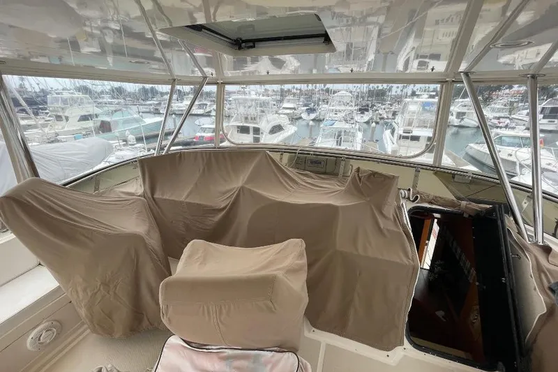 1990 Offshore Yachts 55 Pilothouse interior with covered seating, overlooking marina.