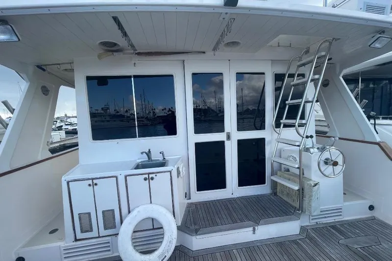 1990 Offshore Yachts 55 Pilothouse deck with sink, ladder, and marina view.