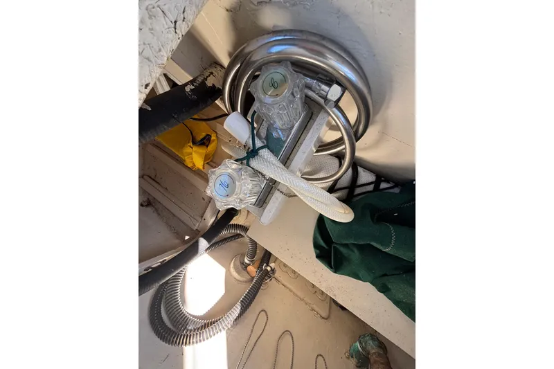 Plumbing system inside 1983 Bristol Channel Cutter 28 sailboat, featuring hoses and valves.