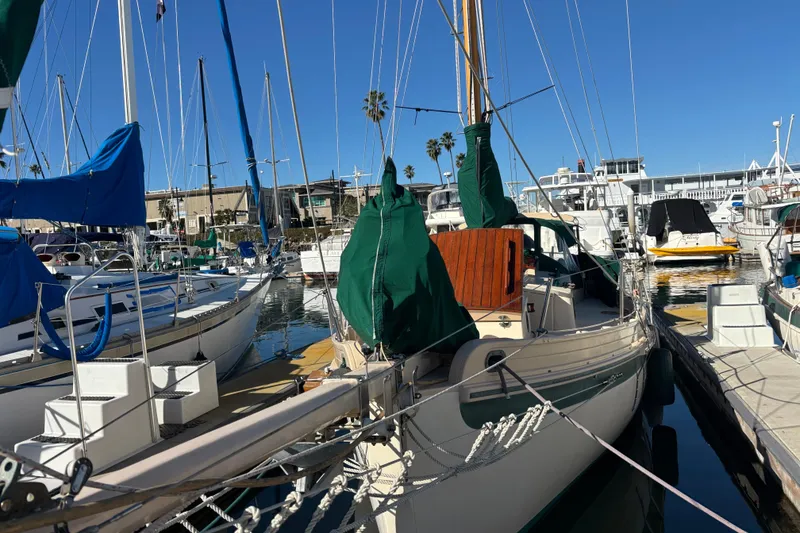 1983 Bristol Channel Cutter 28 docked in a marina, surrounded by other sailboats.