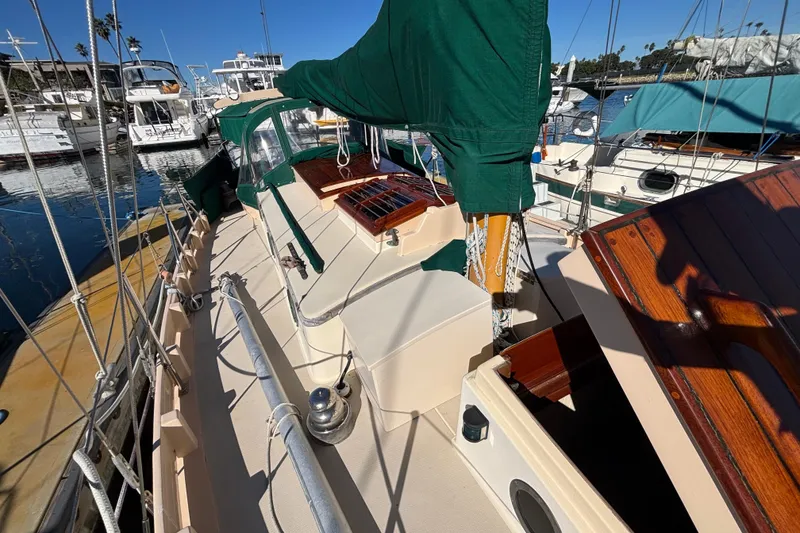1983 Bristol Channel Cutter 28 sailboat with green covers docked in a marina.