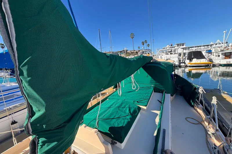 1983 Bristol Channel Cutter 28 sailboat with green covers docked in a marina.