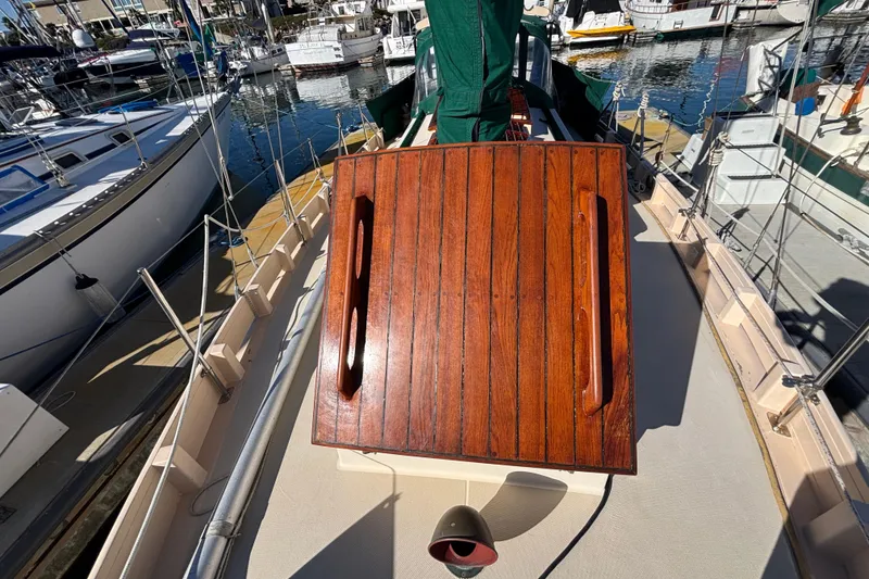 1983 Bristol Channel Cutter 28 sailboat deck with wooden hatch, docked in marina.