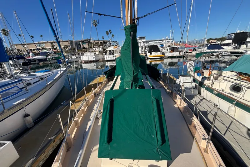 1983 Bristol Channel Cutter 28 sailboat docked in a marina, covered in green tarps.