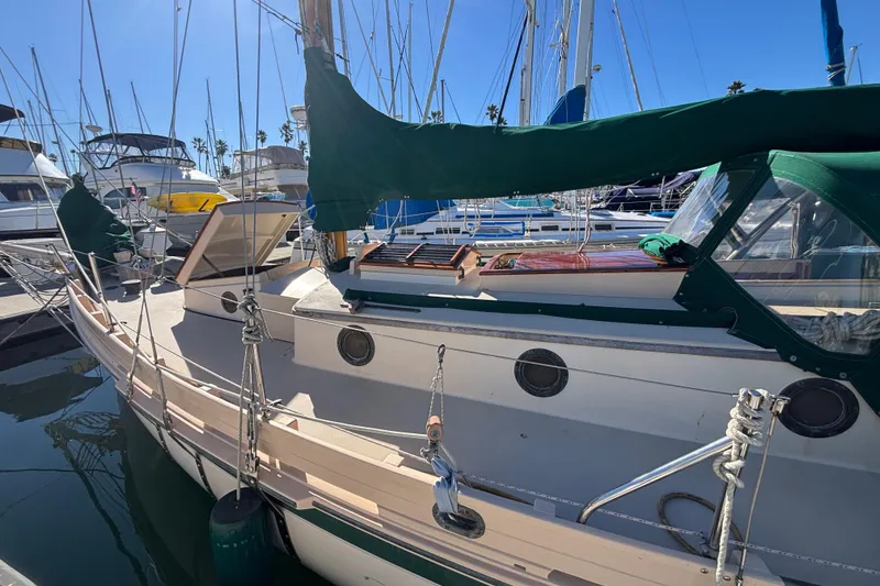 1983 Bristol Channel Cutter 28 sailboat docked in marina, featuring green covers and classic design.