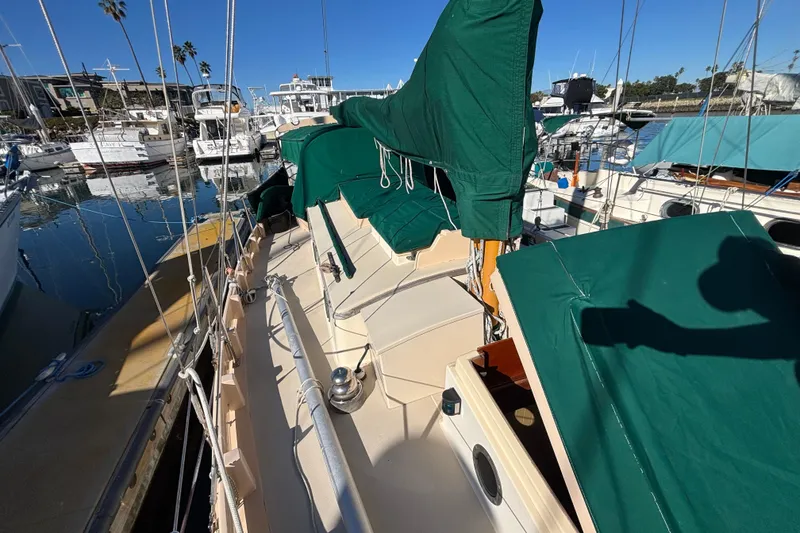 1983 Bristol Channel Cutter 28 sailboat docked, featuring green covers and a sunny marina setting.