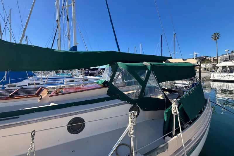 1983 Bristol Channel Cutter 28 sailboat docked in marina with green canopy.