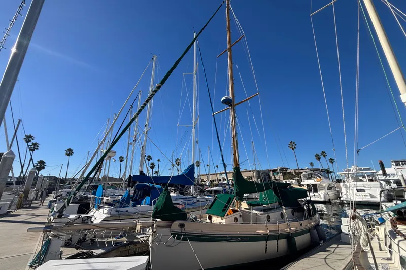 1983 Bristol Channel Cutter 28 sailboat docked at a marina under clear blue skies.
