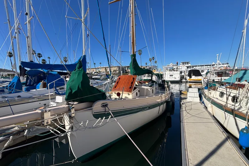 1983 Bristol Channel Cutter 28 sailboat docked in a marina under clear blue skies.