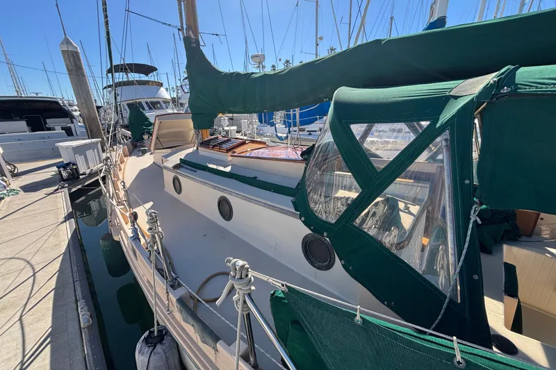 1983 Bristol Channel Cutter 28 docked, featuring green canvas covers and classic design.