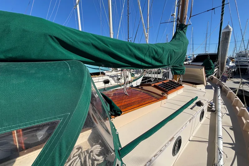 1983 Bristol Channel Cutter 28 sailboat with green covers docked at a marina.