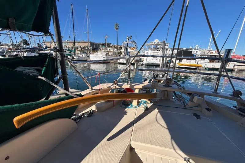 1983 Bristol Channel Cutter 28 sailboat docked in a marina, featuring a wooden tiller.
