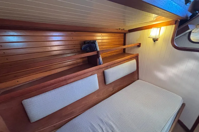 Cozy interior of 1983 Bristol Channel Cutter 28 with wooden paneling and cushioned seating.