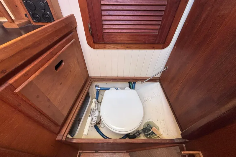 1983 Bristol Channel Cutter 28 boat interior with wooden cabinetry and marine toilet.
