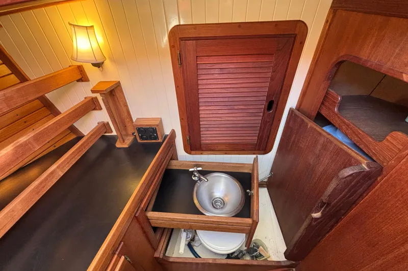 Interior of 1983 Bristol Channel Cutter 28, featuring wooden cabinetry and compact sink.