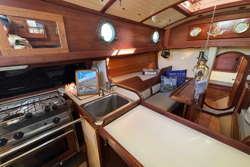 Interior of 1983 Bristol Channel Cutter 28 sailboat with cozy wooden design and kitchen area.