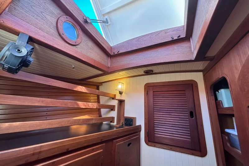Interior of 1983 Bristol Channel Cutter 28, featuring wooden cabinetry and porthole.