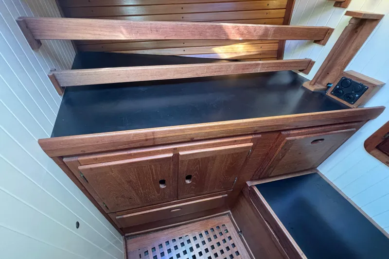 Interior of 1983 Bristol Channel Cutter 28, featuring wooden cabinetry and black countertop.