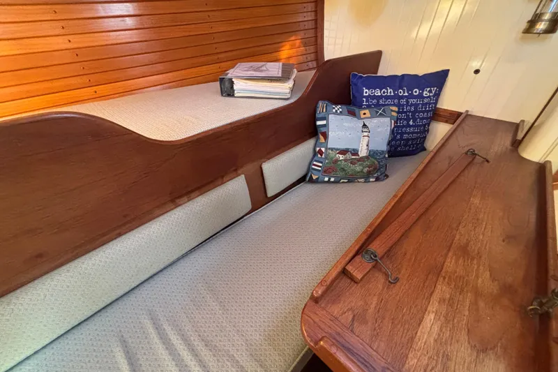 Cozy interior of 1983 Bristol Channel Cutter 28 with nautical-themed cushions and wooden accents.