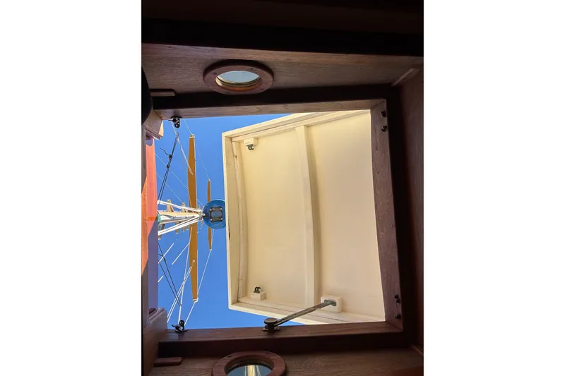View from a 1983 Bristol Channel Cutter 28 hatch, showing mast and clear blue sky.