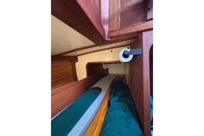 Interior of 1983 Bristol Channel Cutter 28, featuring wooden cabinetry and cozy sleeping area.