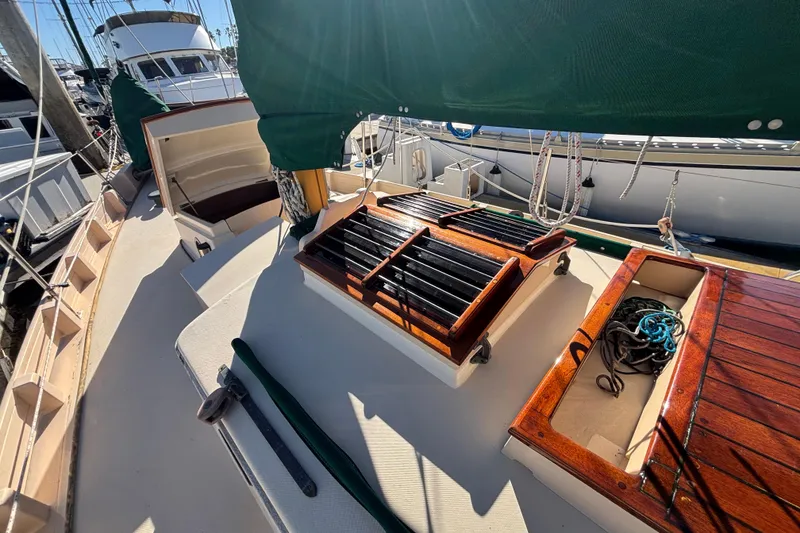 1983 Bristol Channel Cutter 28 sailboat deck with wooden hatches and green canvas cover.