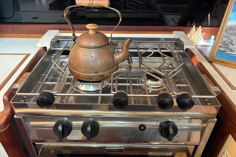 Rustic kettle on stove inside 1983 Bristol Channel Cutter boat kitchen.