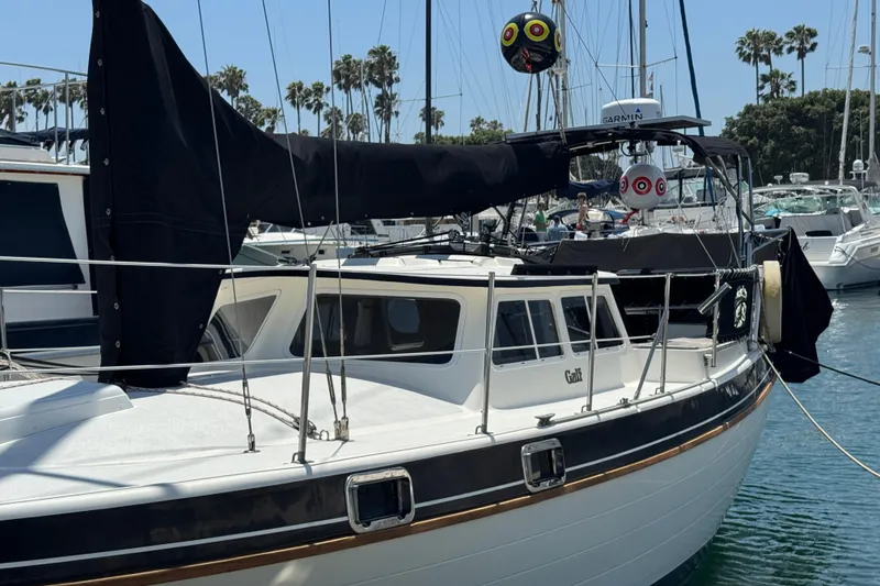 1989 Gulf Pilot House sailboat docked in a marina with palm trees in the background.