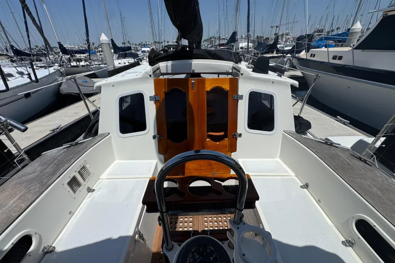 1989 Gulf Pilot House yacht cockpit with wooden doors, docked among sailboats.