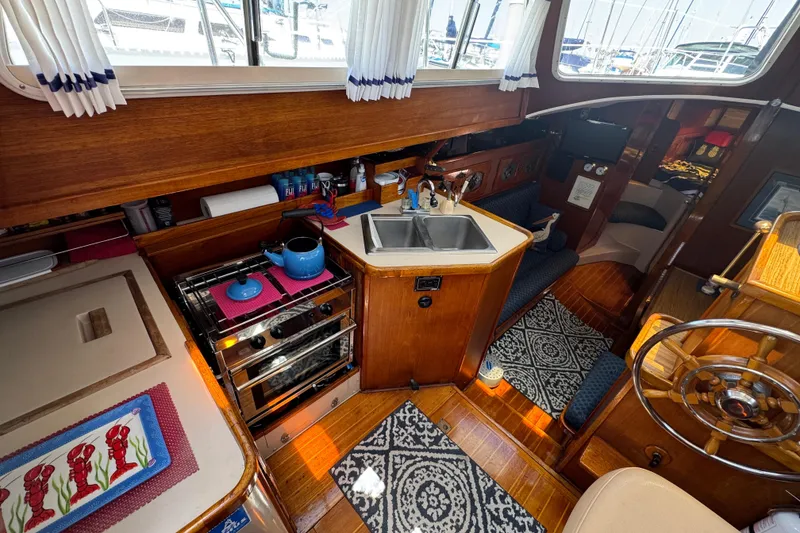 1989 Gulf Pilot House interior with wooden cabinetry, stove, sink, and nautical decor.