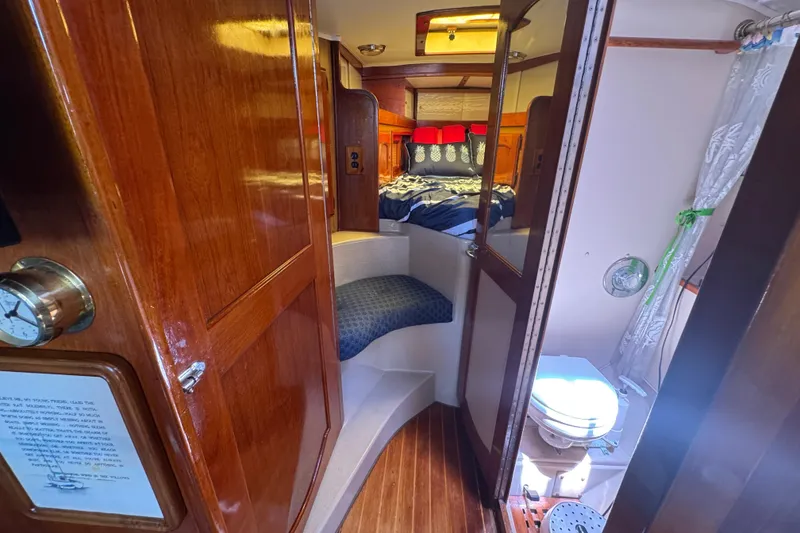 1989 Gulf Pilot House interior with wooden finish, cozy bed, and compact bathroom.