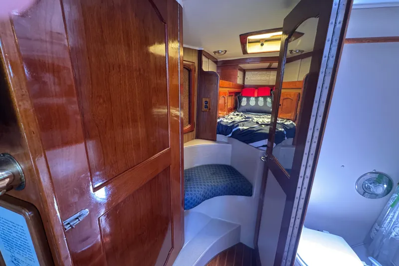 Cozy cabin interior of a 1989 Gulf Pilot House boat with wooden finishes and a comfortable bed.