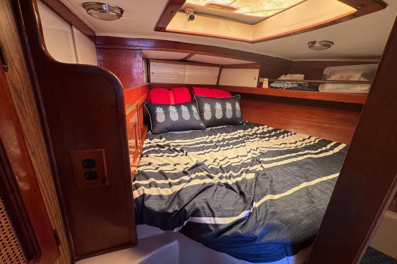 Cozy cabin interior of 1989 Gulf Pilot House with striped bedding and pineapple pillows.